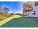 Large, grassy backyard with a newly built home featuring a covered patio and views of the distant trees at 3330 Hillshire Dr, Cumming, GA 30028