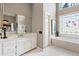 Bathroom featuring tiled floor, white cabinets, garden tub and decorative glass window at 4840 Brent Knoll Ln, Suwanee, GA 30024