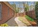 A narrow side yard with a walkway alongside a brick house and a wood fence at 4840 Brent Knoll Ln, Suwanee, GA 30024