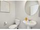Stylish powder room with a pedestal sink, round mirror, and modern art on the wall at 6355 Towhee Way, Morrow, GA 30260