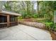 Backyard with concrete patio, stone retaining wall, and mature trees at 1323 Christmas Ne Ln, Atlanta, GA 30329