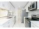 Galley kitchen with sleek white cabinets, modern appliances, and stainless-steel accents at 64 Saint Claire Ne Ln, Atlanta, GA 30324