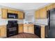 Bright kitchen featuring wood cabinets, black appliances, and durable hardwood flooring at 2760 Carolina Rdg, Riverdale, GA 30296