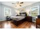 Cozy bedroom with a large bed, wood floors, ceiling fan, and natural light from two windows at 539 Collingwood Dr, Decatur, GA 30032