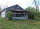 View of a charming home featuring a screened-in porch, surrounded by green grass and leafy trees at 3915 Dahlonega Hwy, Cumming, GA 30028