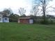 View of an ample backyard featuring a shed and a manufactured home surrounded by trees and green grass at 3915 Dahlonega Hwy, Cumming, GA 30028