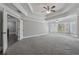 Bedroom with tray ceiling, ceiling fan, large windows, and an open doorway to an adjacent room at 3275 Aldrich Dr, Cumming, GA 30040