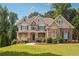 Stunning two-story home featuring a stone and brick facade with a welcoming front porch and beautifully landscaped yard at 3275 Aldrich Dr, Cumming, GA 30040