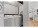 Convenient laundry room featuring a modern washer and dryer with white cabinets for storage at 6160 Lake Lanier Heights Rd, Buford, GA 30518