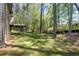Grassy backyard with tall trees offers privacy with an elevated deck on a siding home at 2050 Heritage Green Dr, Marietta, GA 30064
