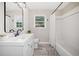 Bathroom showcasing a white vanity, bathtub with shower, a framed mirror, and a large window at 294 Arnold Mill Rd, Woodstock, GA 30188
