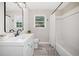 A bright bathroom is designed with neutral walls, a tub with a shower, and a sleek modern mirror at 294 Arnold Mill Rd, Woodstock, GA 30188