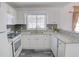 Bright kitchen features white cabinets, granite countertops, stainless steel appliances, and a stylish gray backsplash at 102 Manley Ct, Woodstock, GA 30188