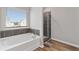 Bathroom featuring a large bathtub, and shower with dark tiling and glass doors at 1052 Bodega Loop, Locust Grove, GA 30248