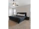Comfortable bedroom featuring a dark bed frame, ceiling fan, and plenty of natural light from the large windows at 1052 Bodega Loop, Locust Grove, GA 30248