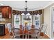 Eat-in kitchen boasts a wood table with white chairs and a window with floral valance at 3227 Heritage Way, Buford, GA 30519