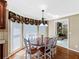 Eat-in kitchen boasts a wood table with white chairs and a window with floral valance at 3227 Heritage Way, Buford, GA 30519