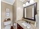 Powder room featuring granite counters, dark wood cabinets, and a decorative mirror at 3227 Heritage Way, Buford, GA 30519
