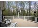 View of the outdoor wooden deck with white railing surrounded by trees and a decorative bird statue and seating area at 1007 Springharbor Walk, Woodstock, GA 30188