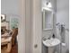 Bright powder room with pedestal sink, mirror, and view into the living room with fireplace at 1007 Springharbor Walk, Woodstock, GA 30188