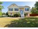 Charming two-story yellow home with landscaped front yard, grey shutters and white stairs at 3540 Owl Brow Ct, Cumming, GA 30028