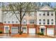 A daytime full exterior view of a 3-unit townhome with brick and siding, plus garages, and light landscaping at 3987 Howell Park Rd, Duluth, GA 30096