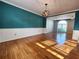 Bright dining room featuring hardwood floors, a teal accent wall, and a modern light fixture at 2875 Oak Meadow Dr, Snellville, GA 30078