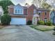 Charming two-story home with a brick and siding exterior, a wide driveway, and green landscaping at 2875 Oak Meadow Dr, Snellville, GA 30078
