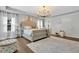 Bright main bedroom featuring tray ceiling, chandelier, hardwood floor, and white trim at 8033 Louis Dr, Locust Grove, GA 30248