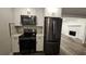 Modern kitchen with stainless steel appliances, white cabinets and stone fireplace located in the living room area at 695 Pine Shadows Dr, Dallas, GA 30157