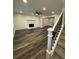 Bright living room features a stone fireplace, modern ceiling fan, and beautiful flooring adjacent to carpeted stairs at 695 Pine Shadows Dr, Dallas, GA 30157