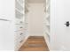 Bright walk-in closet with custom white shelving, drawers, and wood flooring at 220 Alcovy Terrace, Alpharetta, GA 30009