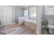 Bright bathroom with soaking tub and glass shower, wood look tile flooring, and white fixtures at 560 Hunt River Way, Suwanee, GA 30024