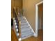 Carpeted staircase featuring decorative metal balusters and hardwood floors, connecting multiple levels of the home at 560 Hunt River Way, Suwanee, GA 30024