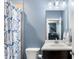 Well-lit bathroom featuring a stylish shower curtain, white vanity, and blue painted walls at 914 Martin Nw St, Atlanta, GA 30318