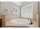 Elegant bathroom featuring a large soaking tub with bronze fixtures and a window for natural light at 552 Lawton Bridge Sw Rd, Smyrna, GA 30082