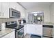 Modern kitchen with stainless steel appliances and a view into the dining and living area at 4095 Stillwater Dr, Duluth, GA 30096
