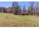 Scenic view of a red barn nestled in a large grassy lot bordered by trees at 692 W Union Grove Cir, Auburn, GA 30011