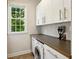 Bright laundry room with modern appliances, white cabinets, and a window with green tree view at 1239 Bonshaw Trl, Marietta, GA 30064