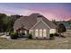 Backyard view showcasing the home's architecture, inviting patio, and lush landscaping against a colorful dusk sky at 179 Country Club Dr, Hiram, GA 30141