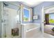A well-lit bathroom showcases a glass shower and a tub underneath a bright window at 179 Country Club Dr, Hiram, GA 30141