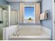 Bathroom features a white tub underneath a bright window and a separate glass shower at 179 Country Club Dr, Hiram, GA 30141