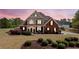 Charming two-story brick home with manicured front yard and elegant exterior lighting at dusk at 179 Country Club Dr, Hiram, GA 30141