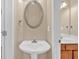 Cozy powder room featuring a pedestal sink with an oval mirror and neutral wall color at 709 Mountain Laurel Dr, Canton, GA 30114