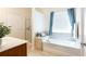 Bright bathroom featuring a soaking tub with tile surround and separate glass shower at 4520 Vanadium Bnd, Cumming, GA 30040