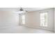 Bright bedroom featuring neutral carpet, ceiling fan, and natural light from two windows at 4520 Vanadium Bnd, Cumming, GA 30040