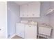 Well-lit laundry room with washer, dryer, utility sink, and ample storage cabinets at 660 Hembree Rd, Roswell, GA 30076