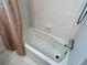 Close up of the bathtub in a bathroom featuring tiled walls, floor, and shower curtain at 5791 Warren Farm Sw Rd, Powder Springs, GA 30127