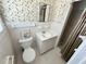 Cozy bathroom featuring a toilet, vanity, and shower with classic white tile and floral wallpaper at 5791 Warren Farm Sw Rd, Powder Springs, GA 30127