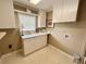 Traditional laundry room with white cabinets, countertops, sink, window and tile flooring at 5791 Warren Farm Sw Rd, Powder Springs, GA 30127